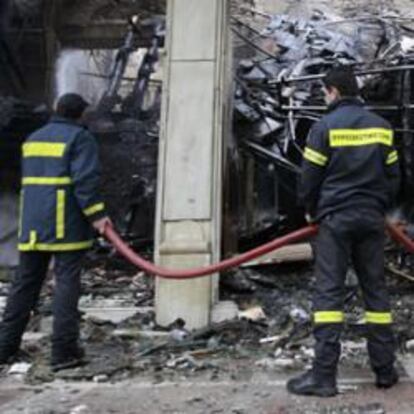 Los bomberos sofocan el fuego de uno de los edificios del centro de Atenas que ardieron en la noche del comingo