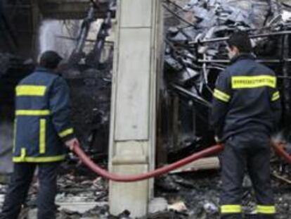 Los bomberos sofocan el fuego de uno de los edificios del centro de Atenas que ardieron en la noche del comingo