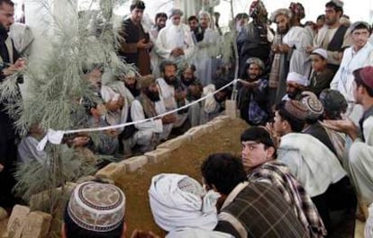 Un grupo de afganos reza sobre la tumba de Ahmad Wali Karzai en Karz, Afganistán