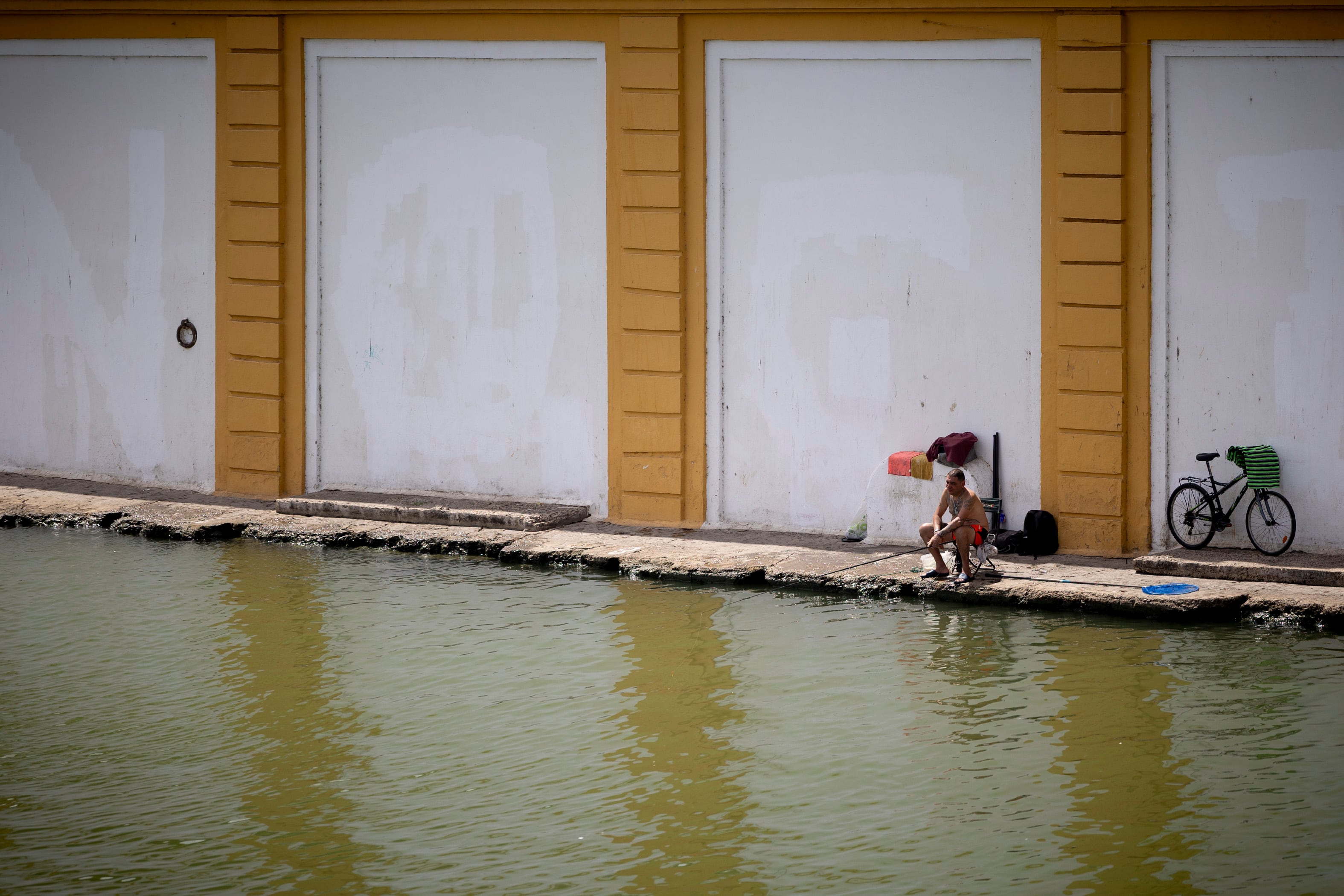 Un hombre pesca en la orilla del Guadalquivir este sábado, en Sevilla.