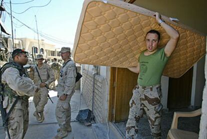 Un soldado español saca un colchón de un edificio de Nayaf, que dejan las tropas españolas, ante la mirada de efectivos estadounidenses.