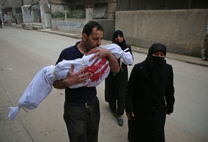 Un hombre besa el cuerpo de su hijo antes del funeral en Zamalka, cerca de Damasco (Siria).