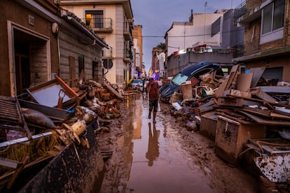 Efectos de la dana en la calle Cresenci Chapa, Catarroja, el 5 de noviembre de 2024. Una semana después de la catástrofe, la escena aún era impactante: una mezcla de barro, muebles y coches destrozados llenaban las calles. En medio de este paisaje, un hombre se acercaba cubriéndose el rostro con la mano, una imagen que resume la desolación en esta localidad. 