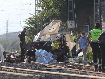 Miembros de los servicios de emergencia retiran restos del vehículo en el que cuatro personas han fallecido tras colisionar en un paso a nivel de la estación alicantina de Novelda.