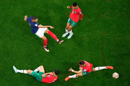 Kylian Mbappé, arriba a la izquierda, dispara a portería ante la presión de tres jugadores marroquíes en el partido de semifinales del Mundial de Qatar.