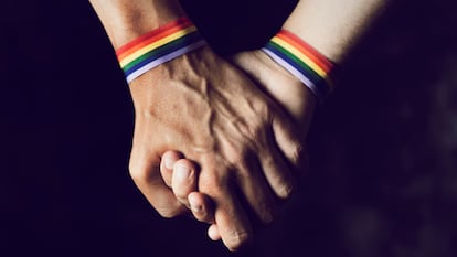 Dos hombres se dan la mano con una pulsera del orgullo LGTBI en sus muñecas.