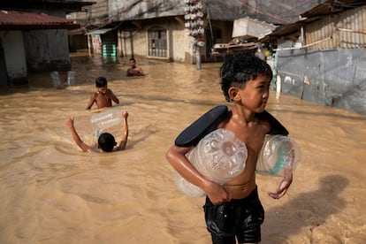 Niños juegan en una calle inundada tras el paso del tifón Man-Yi, en Cabanatuan