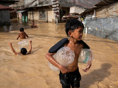 Niños juegan en una calle inundada tras el paso del tifón Man-Yi, en Cabanatuan