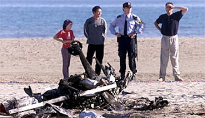 Un agente contemplaba con otras personas los restos del ultraligero autogiro accidentado en la playa del Serradal de Castellón