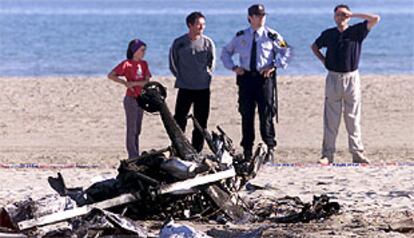 Un agente contemplaba con otras personas los restos del ultraligero autogiro accidentado en la playa del Serradal de Castellón