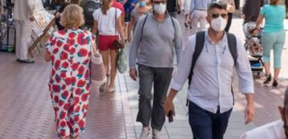 Rranseúntes se protegen con mascarillas por las calles.  .