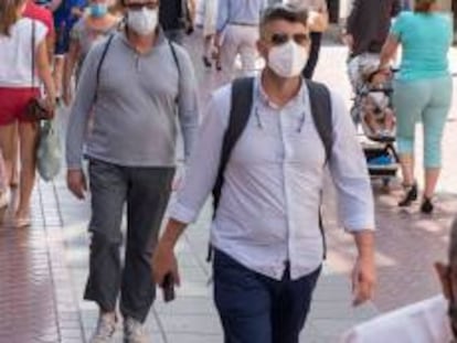 Rranseúntes se protegen con mascarillas por las calles.  .