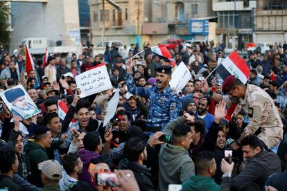 Manifestantes carregam policiais iraquianos comemorando a vitória sobre o EI em Bagdá.