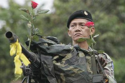 Un soldado decora su ametralladora con dos flores recibidas de la gente y una cinta amarilla de lealtad al rey.