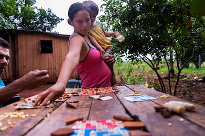 Cintia sostiene a su hijo mientras juega a la lotería con vecinos en el barrio de Cuatro Bocas.