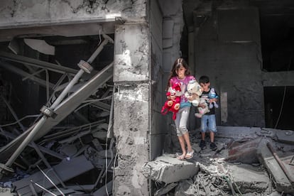 Niños palestinos salen de su casa tras recuperar varios juguetes en la torre de Al-Jawhara en la ciudad de Gaza, que resultó muy dañada por los ataques aéreos israelíes.  