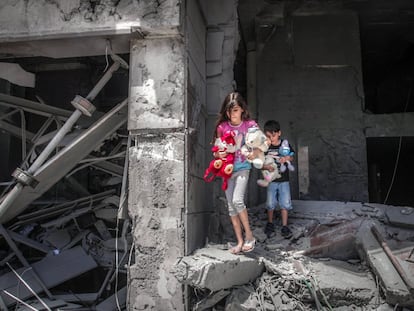 Niños palestinos salen de su casa tras recuperar varios juguetes en la torre de Al-Jawhara en la ciudad de Gaza, que resultó muy dañada por los ataques aéreos israelíes.  