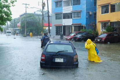 Personas atraviesan una calle inundada de la ciudad de Cancun, este 25 de septiembre.