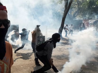 Manifestantes jogam de volta bombas de gás lacrimogêneo à polícia durante um protesto contra o Governo, na quarta-feira em Caracas.