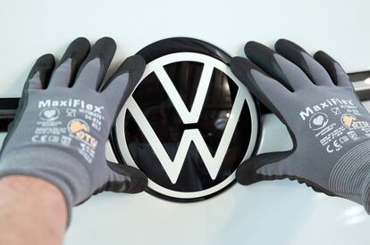 Un empleado de Volkswagen colocando el logotipo de la marca en un coche