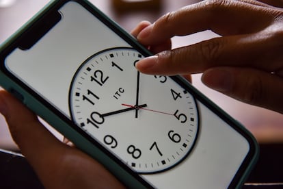 Una persona cambia la hora en el reloj de su teléfono celular.