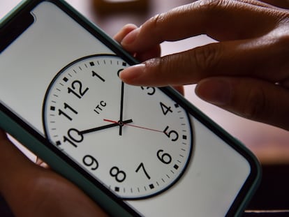 Una persona cambia la hora en el reloj de su teléfono celular.