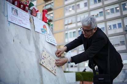 Un hombre pega un dibujo donde se puede leer "Que te mejores pronto papa Francisco" en la estatua del papa Juan Pablo II en el exterior del hospital Gemelli de Roma, este lunes. 