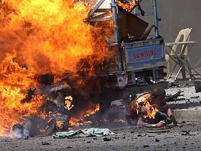 Un hombre se quema y otro se arrastra lejos del fuego segundos después de la explosión de un coche bomba ayer en Bagdad.