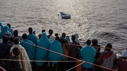 Varias personas rescatadas por la ONG Open Arms en el mediterráneo central observan un bote de goma hundido en el mar de Alborán (27/12/2018).