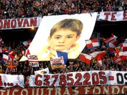 Aficionados del Atlético de Madrid despliegan un enorme cartel con la imagen de Dónovan y el número de teléfono de su familia.