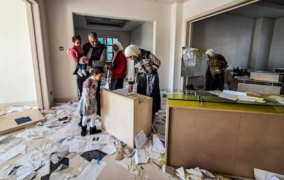 Una familia curiosea los documentos abandonados en una de las estancias de la mansin de El Asad en Damasco.