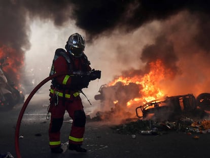 Un bombero junto a varias motos ardiendo en París.