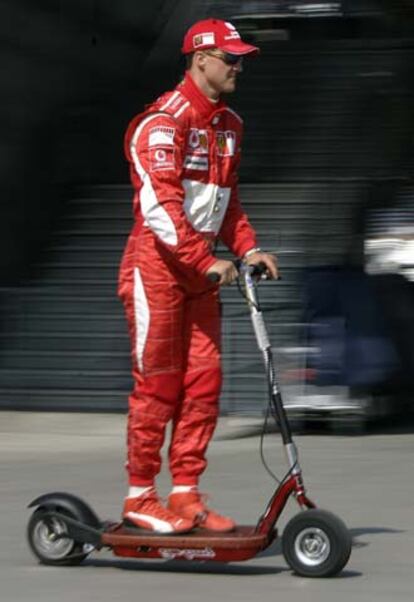 Michael Schumacher pasea por el <i>paddock</i> en un patinete eléctrico.