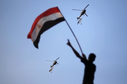 Cinco helicópteros militares rodean la plaza Tahrir de El Cairo portando banderas egipcias durante las protestas multitudinarias, 1 de julio de 2013. Al menos doce personas han muerto en las últimas horas en los enfrentamientos entre islamistas y opositores en la sede central de los Hermanos Musulmanes en El Cairo, lo que eleva a veinte el número de fallecidos desde anoche en todo el país.