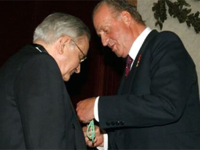 Don Juan Carlos impone al ex gobernador del Banco de España nuevo académico la medalla que le acredita como nuevo académico.