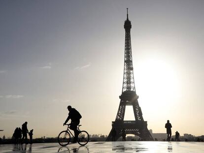 Un ciclista y varios paseantes, frente a la torre Eiffel de París.