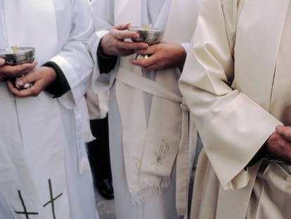 Sacerdotes con cálices durante una misa.