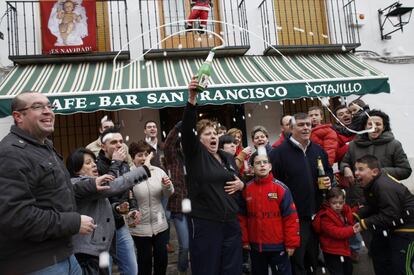 Un grupo de clientes del bar "San Francisco" de Almagro (Ciudad Real), que lleva muchos años abonado al número 42.653 y fueron agraciados con el segundo premio de la lotería de "El Niño", muestran un décimo premiado mientras celebran su suerte ante el local.