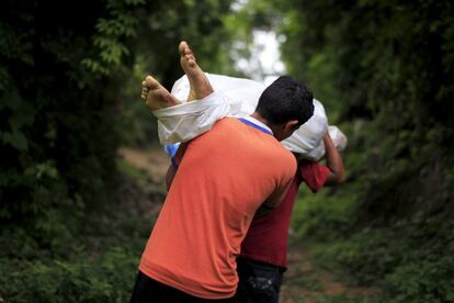 Dos hombres transportan el cadáver de un miembro de la pandilla Barrio 18 en la localidad de San Pedro de Perulapán (El Salvador).