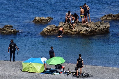 Os efetivos policiais não deram abasto e mais de uma centena de jovens entraram em Ceuta pela zona do Tarajal sem problemas. Na imagem, um agente da policial local vigia vários imigrantes, na segunda-feira.