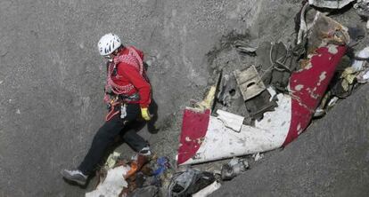 Un miembro de los equipos de rescate junto a restos del avión.