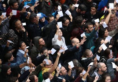 Pessoas mostram suas cédulas do lado de fora de um colégio durante a jornada do referendo independentista em Catalunha.