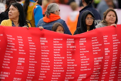 Mujeres indígenas sostienen el telón rojo que lleva inscritos los nombres de los menores fallecidos en la red de internados. Las palizas, las agresiones sexuales, el abandono, el racismo y el repudio cultural fueron algunas de las prácticas denunciadas en esos internados.