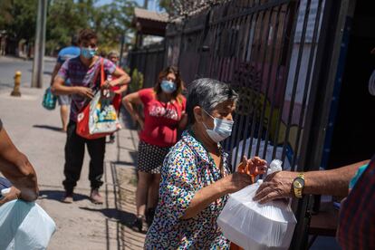 Vecinos de la población Colombia reciben alimento de un comedor solidario, en La Pintana.