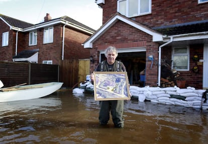 El constructor Derek Bristow de 64 años posa frente a su casa con una de las fotos que rescataría si el agua inundase su casa en Moorland (Inglaterra), 16 de febrero de 2014.