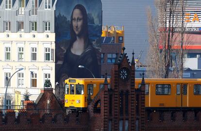 Un tren subterráneo U-Bahn pasa frente a un mural de la banda de arte callejero 'Die Dixons' (Los Dixons) con sede en Berlín, que muestra una reproducción gigante de la Mona Lisa de Leonardo Da Vinci, cerca de la East Side Gallery.