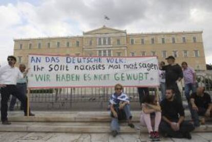 Unos manifestantes se concentran con una pancarta en la que se lee, en alemán: "Al pueblo alemán: la próxima vez no podréis decir que no lo sabíais" durante una concentración frente al Parlamento griego en Atenas, Grecia. EFE/Archivo