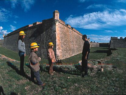 Niños con casco, dispuestos para la aventura, junto al foso de la fortaleza de Sant Ferran.