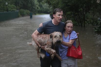 Um homem acompanha mulher que resgatou da casa dela em River Oaks, um bairro rico de Houston.