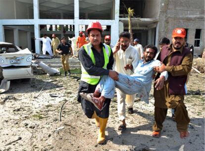 Dos personas transportan a un hombre herido por el atentado en Peshawar.